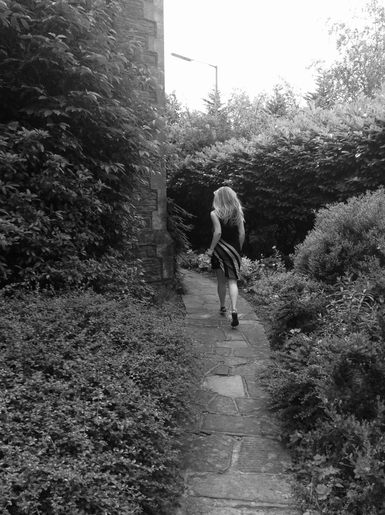 a girl walking through hedges alone